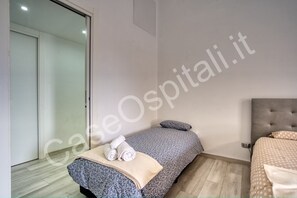 A hotel room with a bed, a bedside table, a wall-mounted TV, and a sliding door leading to a bathroom.