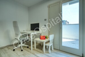 Une pièce comprenant un bureau, une chaise, un téléviseur et une fenêtre.