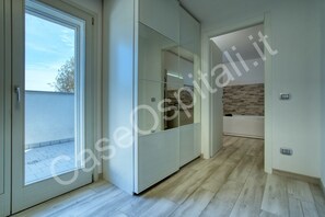 A modern interior with a sliding glass door leading to an outdoor area, a glass-fronted wardrobe, and a visible bathroom with a bathtub.