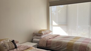 A bedroom with two beds, a window, and a ceiling fan.