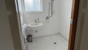 A small, clean bathroom with a window, a sink, and a shower.