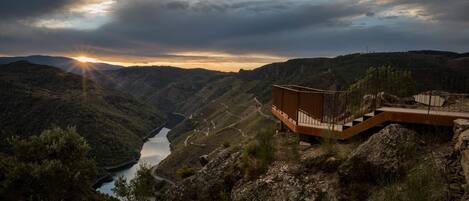 A modern building with a wooden structure overlooking a valley with a river.