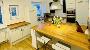 Eine moderne Küche mit weißen Schränken, einer Holz Arbeitsplatte und einer zentralen Kochinsel mit Barhocker.