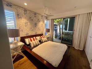 Une chambre à coucher comprenant un lit, une table de chevet, une lampe et une vue sur l’extérieur grâce à une porte-fenêtre coulissante.