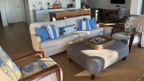A living room with a sofa, armchairs, a coffee table, and a kitchen area in the background. - Wombarra Beach House with Ocean views 
Sleeps 8 (Wombarra)