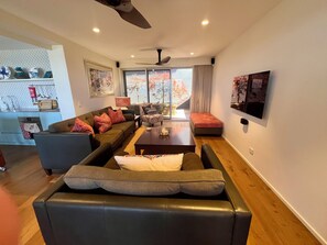 Un salon moderne comprenant un canapé, des fauteuils, une table basse et un téléviseur.