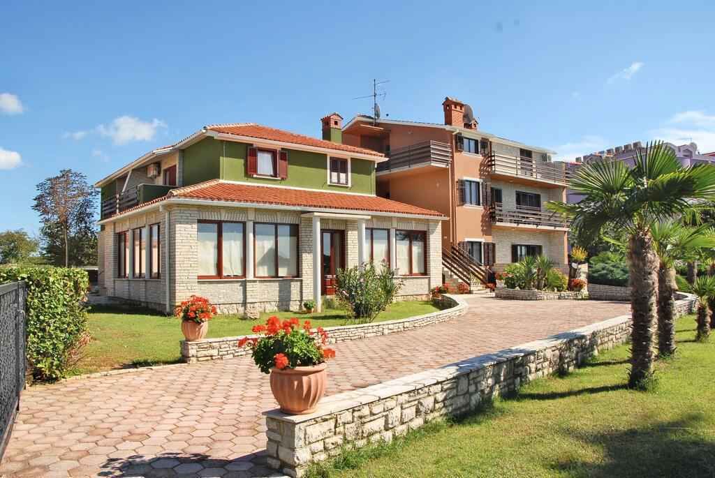 Una casa de dos pisos con fachada de ladrillo, ventanas grandes y un camino de entrada pavimentado.