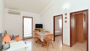 A dining area with a table set for four, a television in the background, and a door leading to another room.
