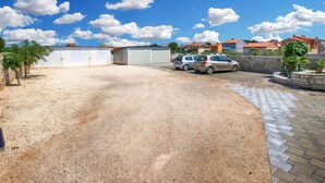 Un espace de stationnement réservé aux petites voitures, une allée gravillonnée et un chemin pavé menant à un bâtiment doté d’un toit rouge.