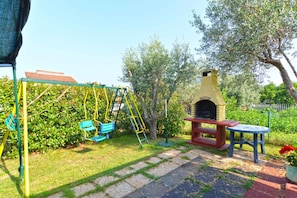 A patio with a swing set, a barbecue grill, and a small table.