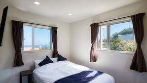 Une chambre d’hôtel avec un lit, une table de chevet et deux fenêtres avec des rideaux.
