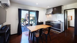 Une cuisine moderne avec une table et des chaises en bois, une cuisinière encastrée et une grande fenêtre avec des rideaux.