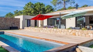 Une maison moderne dotée d’une piscine, de murs en pierre et de mobilier d’extérieur.