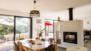 Un espace repas moderne avec une grande table, des chaises et un luminaire suspendu.