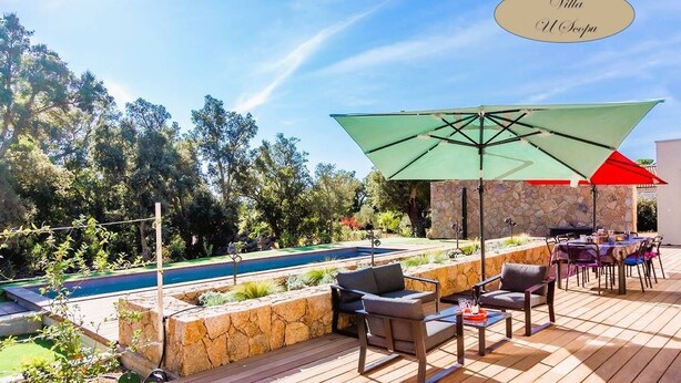 Une terrasse extérieure avec une piscine, des murs en pierre et du mobilier d’extérieur.