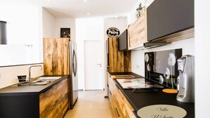 Une cuisine moderne avec des meubles en bois, un plan de travail noir et une machine à café.