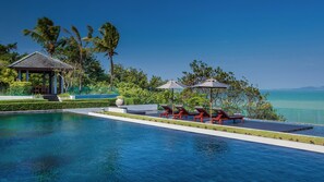 A pool area with lounge chairs and a gazebo, surrounded by palm trees and a view of the sea. - Villa Sawarin (Pa Klok)
