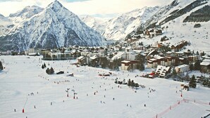 A snow-covered mountain town with ski slopes and buildings. - Près du Télémixte du Diable |  T2 moderne + vue (Les Deux Alpes)