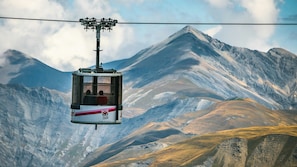 Une télécabine transportant des passagers, suspendue au-dessus d’un paysage montagneux.