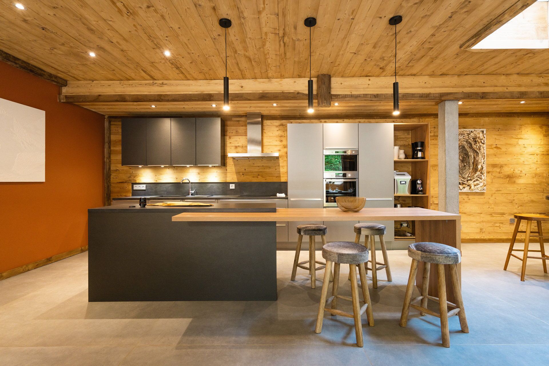 Una cocina moderna con una isla central, taburetes de bar y electrodomésticos integrados.