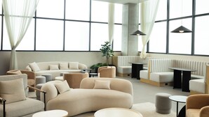 A spacious living room with a large sectional sofa, round coffee tables, and a comfortable seating area with a view of the city skyline through large windows. - Margot. Expo (Guadalajara)