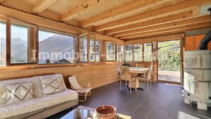 Eine Holzhütte mit einer Couch, einem Esstisch, Stühlen und einem Kamin.