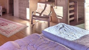 Ein gemütlicher Holzraum mit einem Bett, einem Sessel, einer Couch und einem kleinen Tisch.