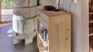 Ein Holzkabinett mit einer Steinsäule, einer Holztreppe und einer Tür, die nach draußen führt.