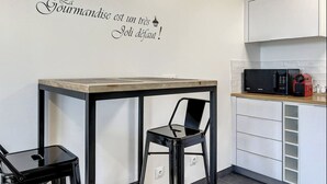 Eine moderne Küche mit Schwarz-Weiß-Farbschema, ausgestattet mit einem kleinen Esstisch und Stühlen, einer Mikrowelle und einer roten Kaffeemaschine.