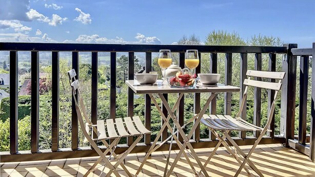 Ein Balkon mit einem Tisch, gedeckt für das Frühstück, einschließlich einer Schüssel, einem Teekessel und Gläsern Orangensaft.