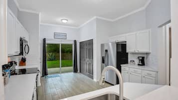 A modern kitchen with white cabinets, a stainless steel sink, and a black refrigerator.