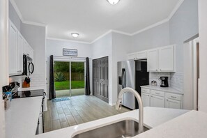 A modern kitchen with white cabinets, a stainless steel sink, and a black refrigerator. - ~Spacious 4/2 in Oakleaf, pet friendly (Orange Park)