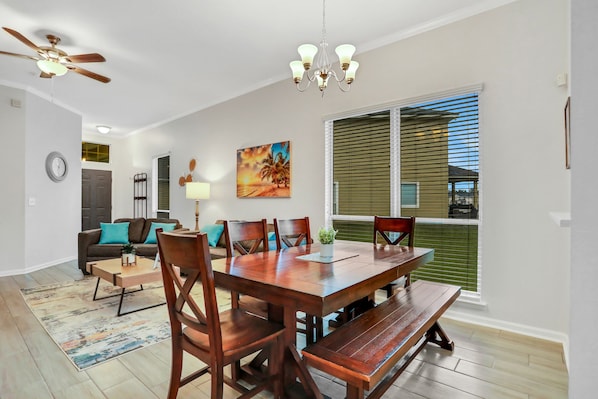 A dining area with a wooden table, chairs, and a bench. There is a ceiling fan, a chandelier, and a painting on the wall. - ~Spacious 4/2 in Oakleaf, pet friendly (Orange Park)