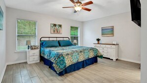 A bedroom with a bed, nightstands, a dresser, a ceiling fan, and two windows with blinds. - ~Spacious 4/2 in Oakleaf, pet friendly (Orange Park)