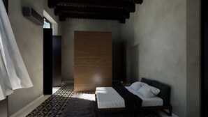 A modern bedroom with a bed, a wooden panel wall, patterned flooring, and a ceiling with traditional architectural elements. - San Patricio Hotel Boutique (Mérida)