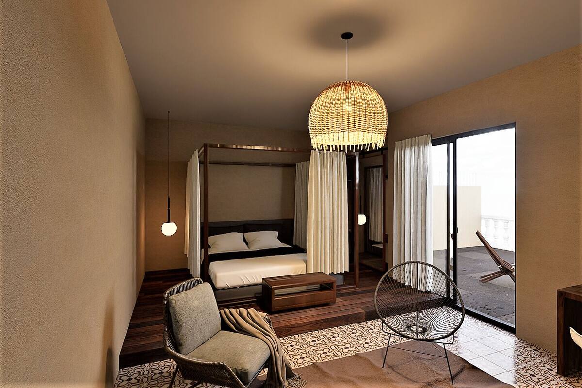 A bedroom with a four-poster bed, a wicker chair, a small table, and a balcony with a chair.