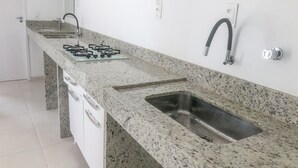Una cocina con encimera de granito, pileta de acero inoxidable y estufa a gas.