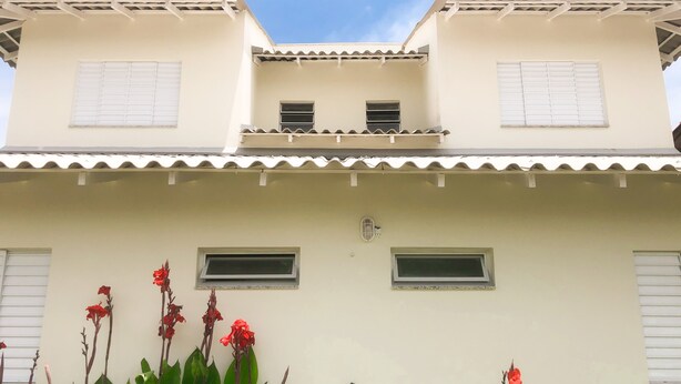 Un edificio de dos pisos con techo plano y detalles blancos. Tiene dos ventanas en el piso superior y dos en el piso inferior.