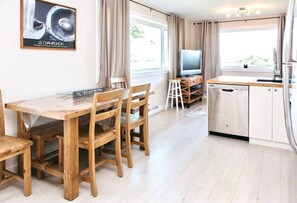 A modern kitchen with wooden furniture, a television, and a refrigerator. - Stunning Beach Front Suite 15min To Downtown! (Victoria)