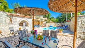 An outdoor patio with a pool, stone walls, and seating areas.
