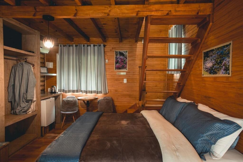 Um quarto acolhedor em cabana de madeira, com uma cama, uma escrivaninha e uma cadeira.