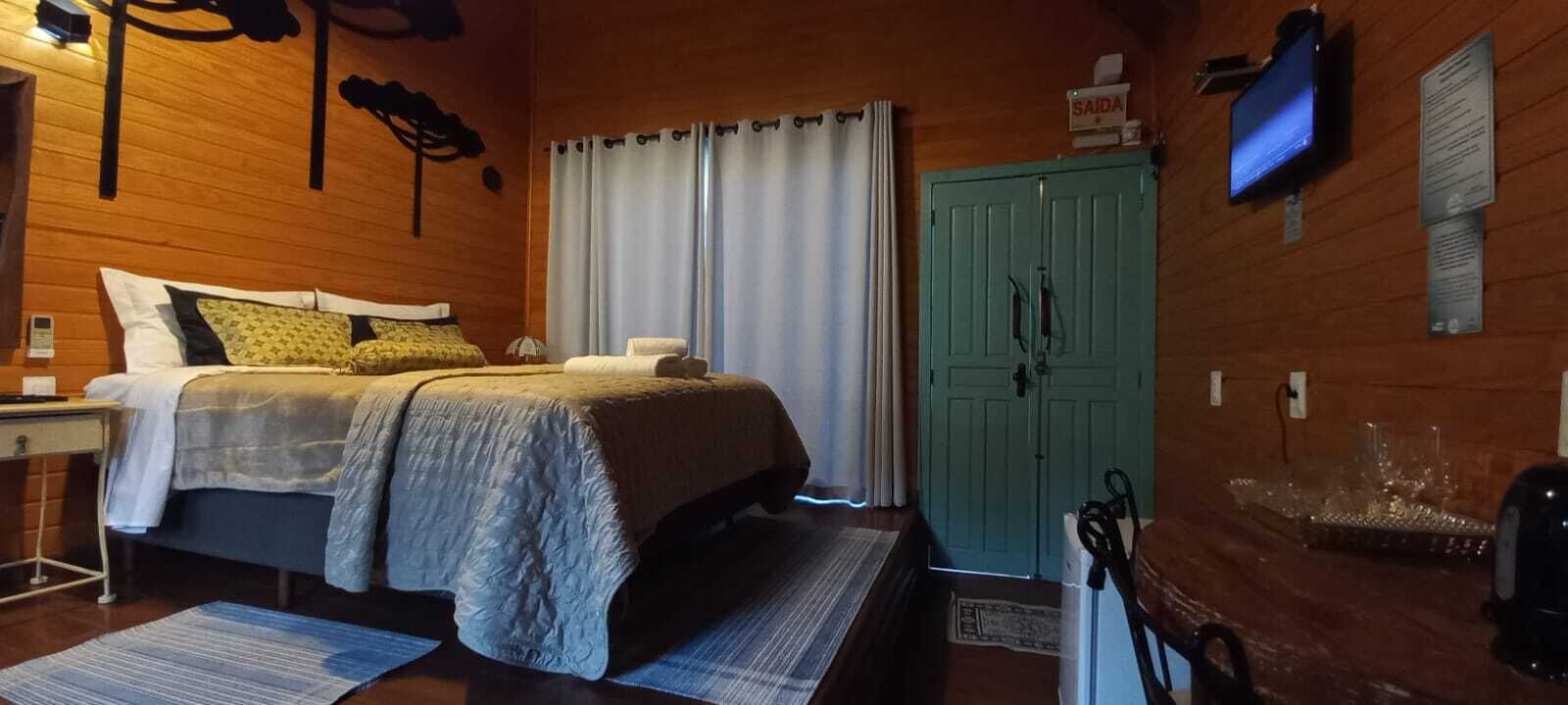 Ein gemütliches Zimmer mit einem Bett, einem Fernseher, einer grünen Tür und einem kleinen Tisch mit Gläsern.
