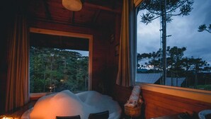 Una habitación con un ventanal grande, detalles de madera en el interior y un objeto blanco y abovedado en el suelo.