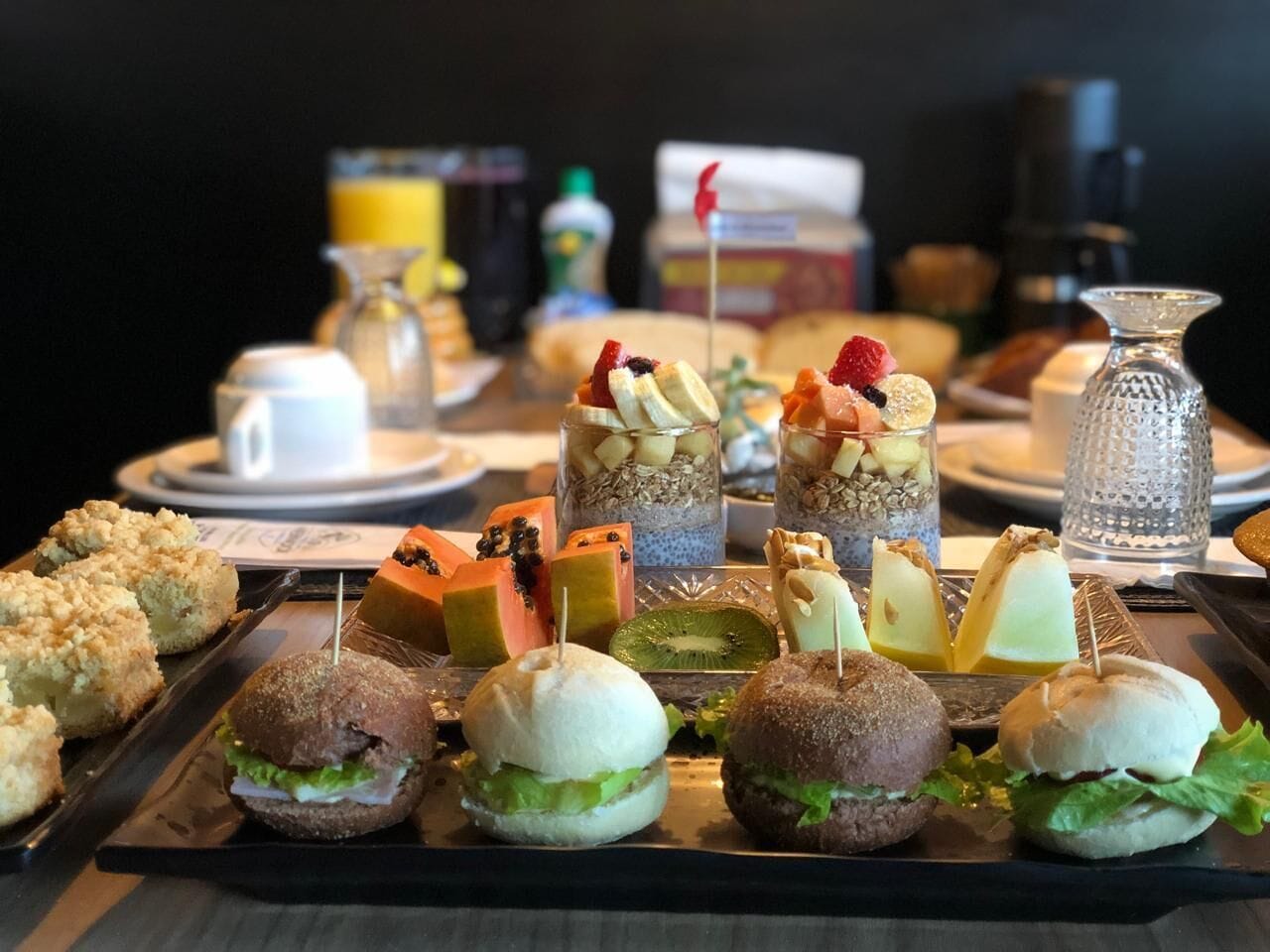Una mesa de bufé con diversos alimentos, entre ellos sándwiches, postres y una estación de café.