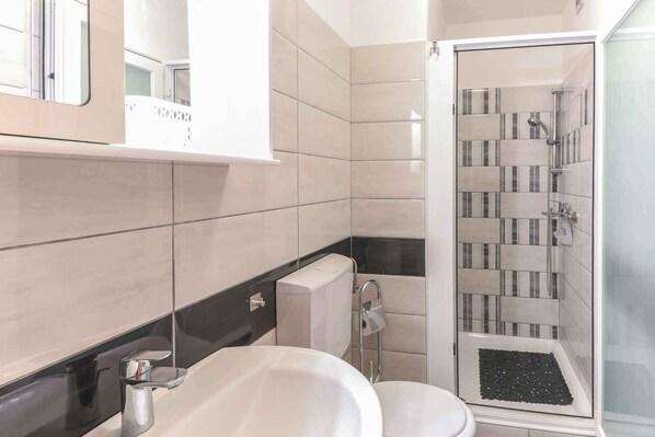 A modern bathroom with a shower, toilet, and sink.