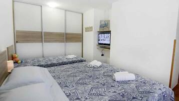 Una habitación de hotel con dos camas, un televisor y un armario.