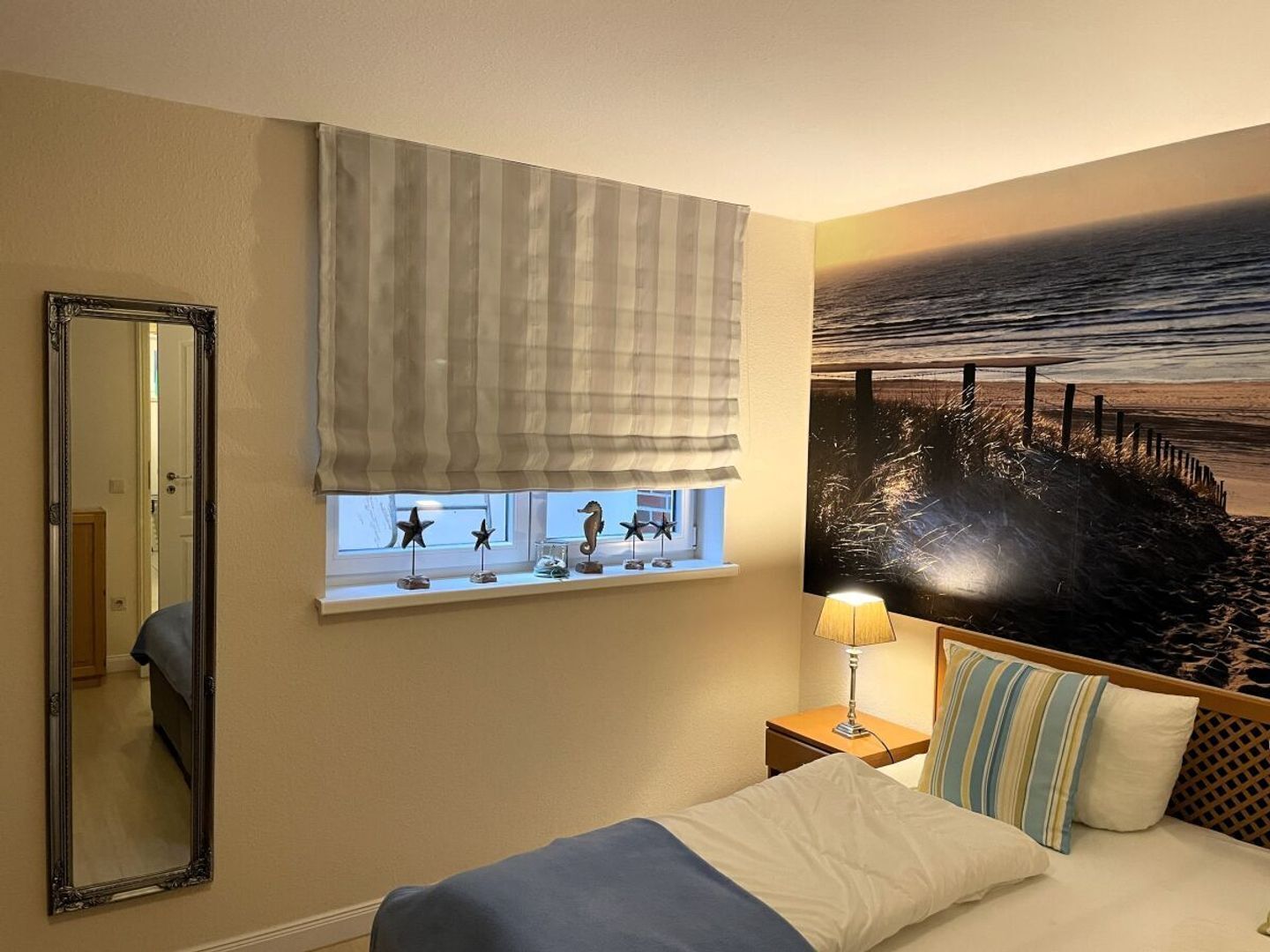 Ein Hotelzimmer mit Bett, Fenster mit Meerblick, Spiegel und Lampe.