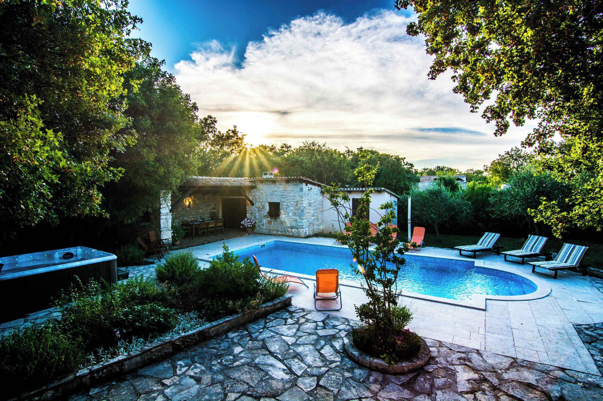A swimming pool with lounge chairs, a hot tub, and stone pathways.