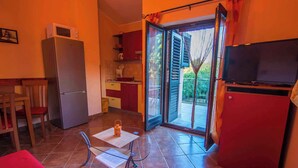 Una cocina compacta con refrigerador, microondas y comedor con mesa y sillas.