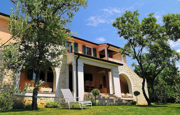 Stunning two-story building with a flat roof, featuring a prominent entrance and lush green surroundings.